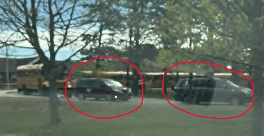 Vans circled in red at a D-Y school parking lot, used for long-distance transportation of homeless / unhoused students under the McKinney-Vento Act